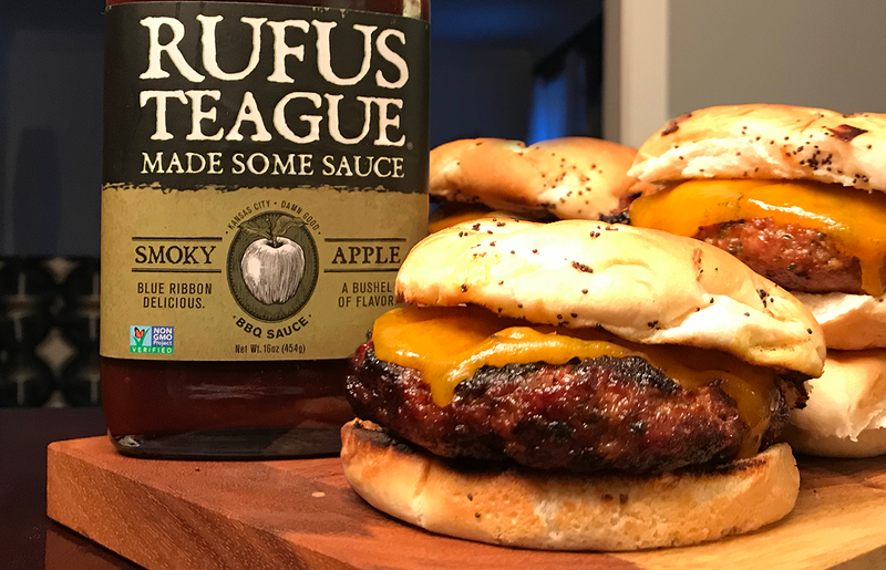 Burgers laying on cutting board with apple sauce.