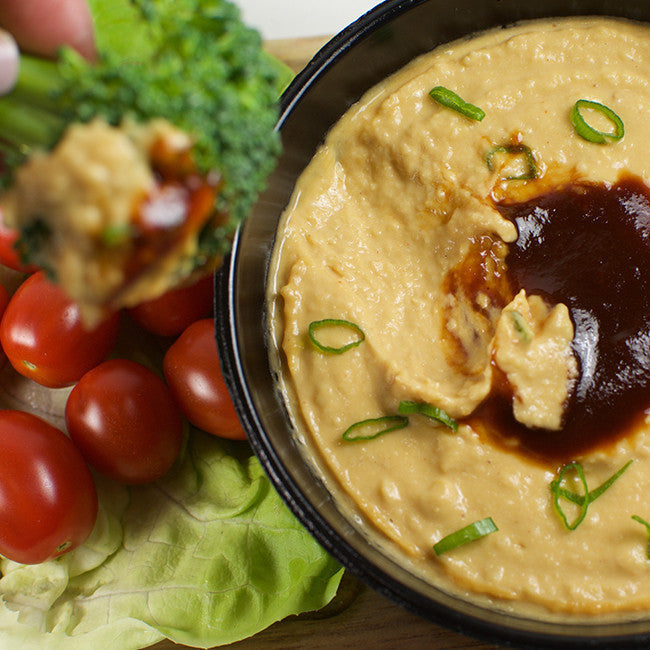 big bowl of hummus with bbq sauce tomatoes etc