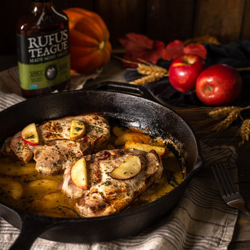 Apple cider and sage pork chops in cast iron skillet with apples and Rufus Teague Smoky Apple